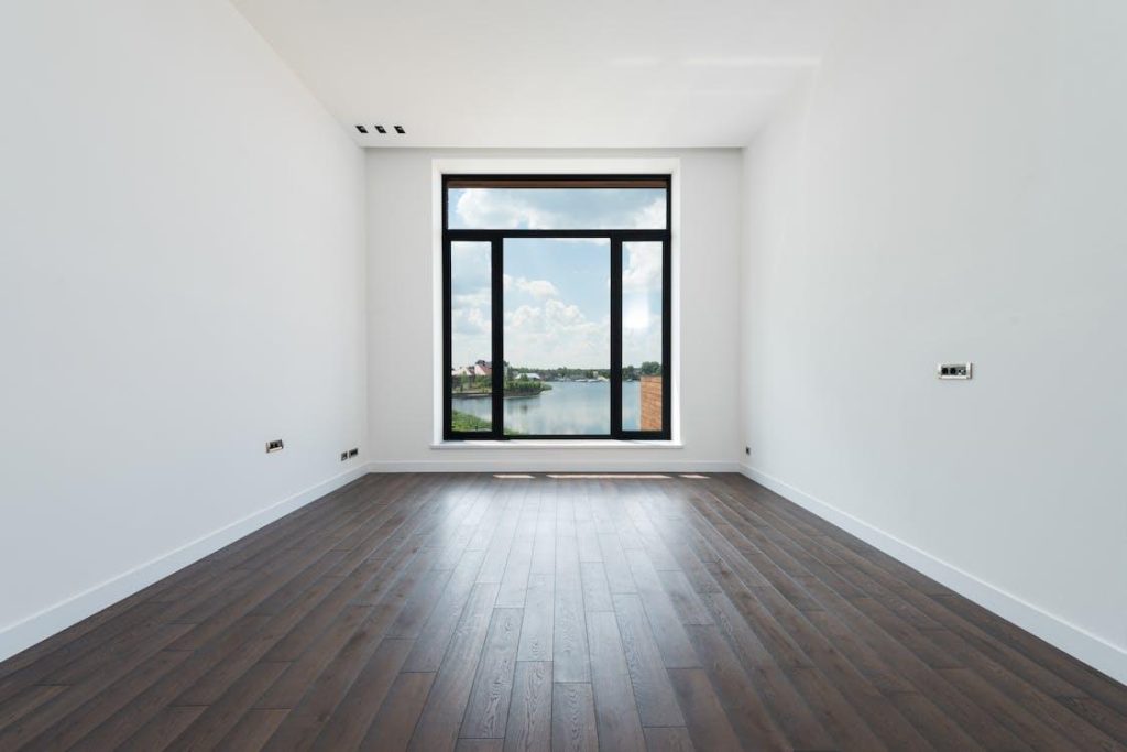 Free Interior of modern spacious light room with wooden laminate floor white walls and panoramic windows Stock Photo