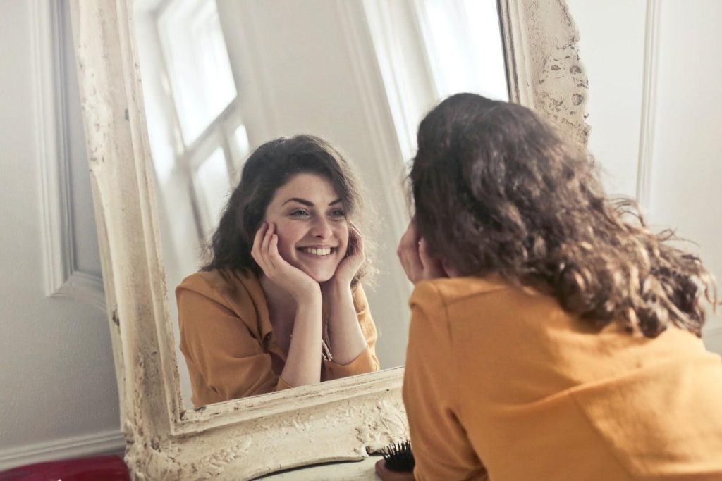 Brunette woman smiling into a mirror