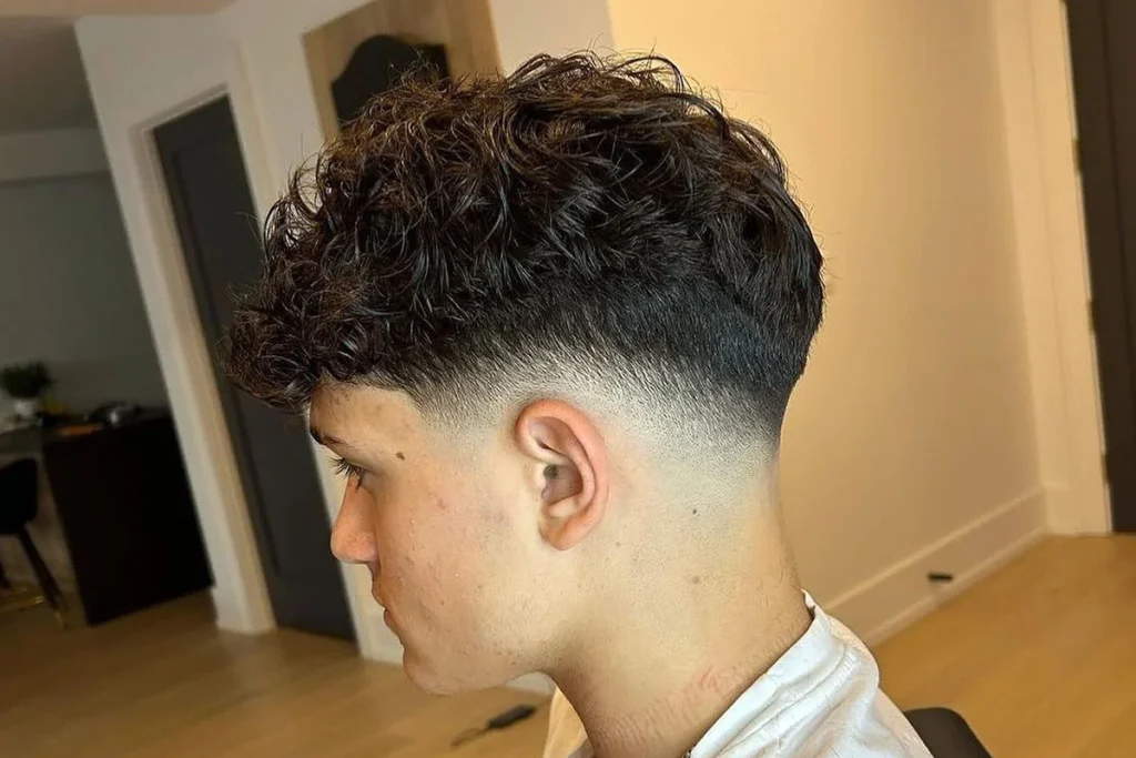 A side profile of a man with a low drop fade and a textured top.