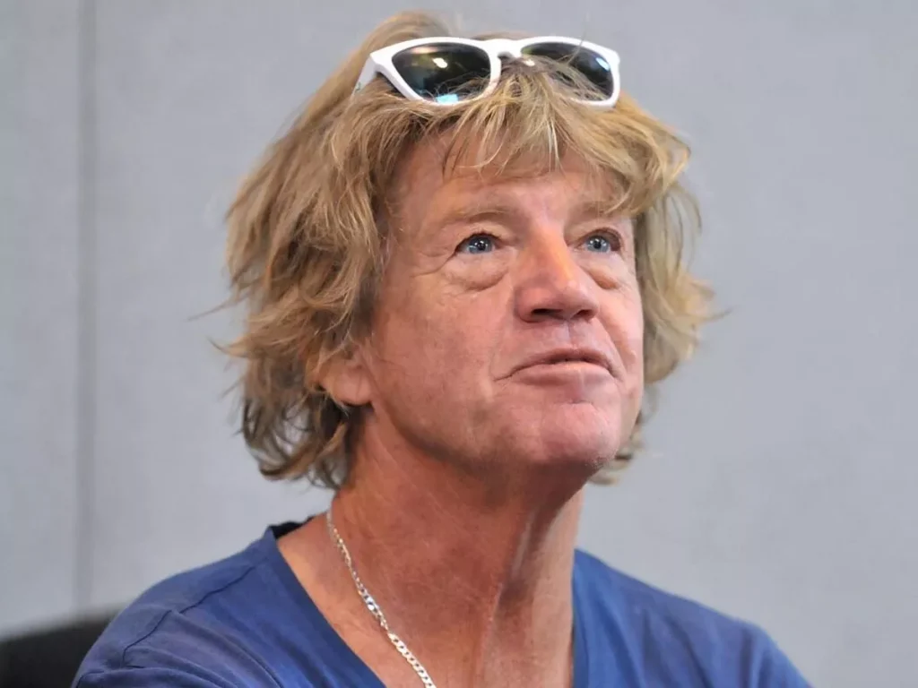Robin Askwith with his signature shaggy hairstyle and sunglasses resting on his head